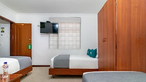 Een hotelkamer met twee éénpersoonsbedden, een houten garderobe, een aan de muur bevestigde televisie en een raam met zonwering.