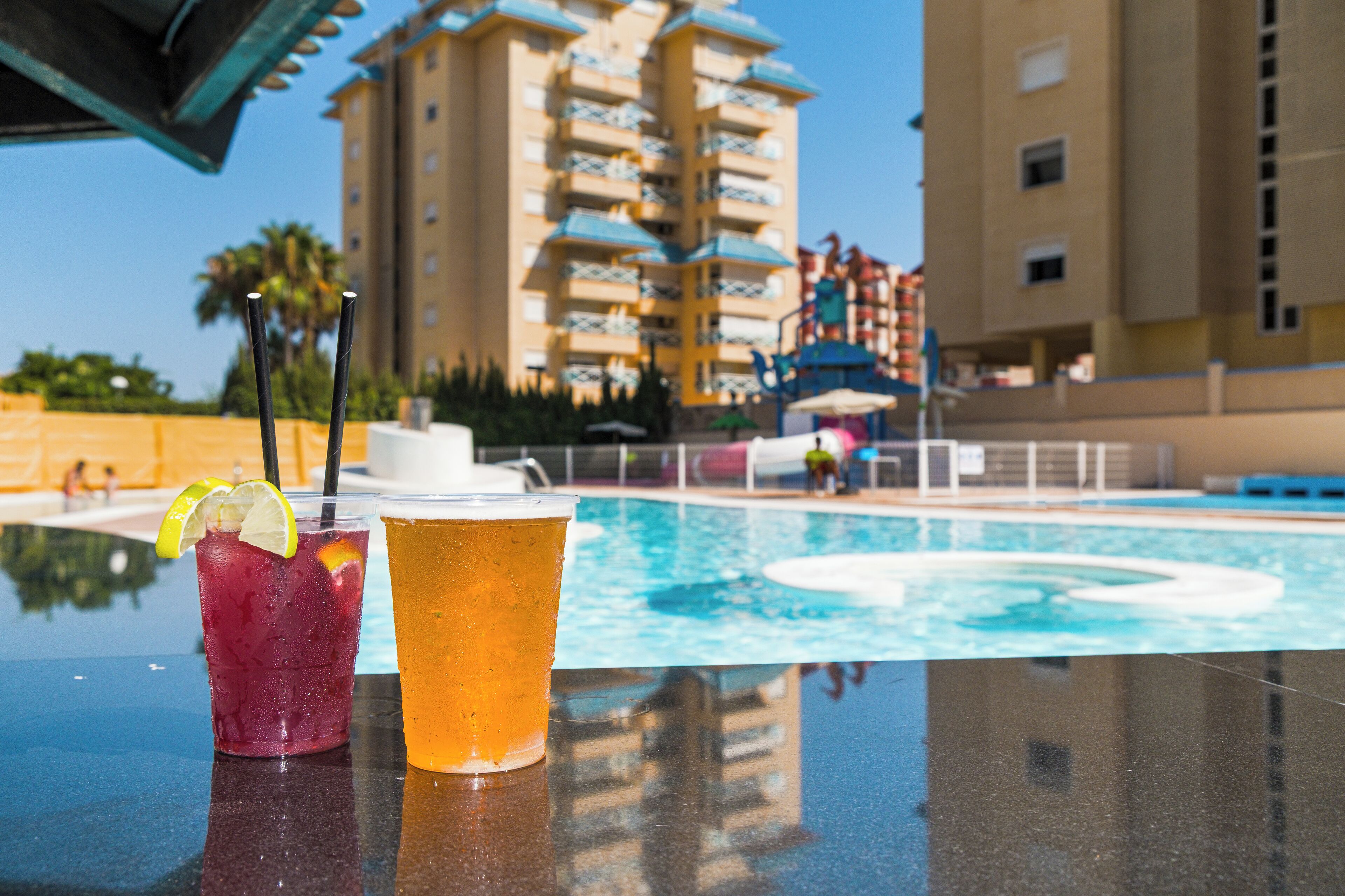 Blick auf einen Pool, mit einem Getränk und Pool im Hintergrund.