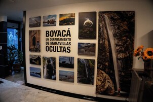 Una pared con múltiples fotografías enmarcadas y un letrero que dice 'BOYACÁ UN DEPARTAMENTO DE MARAVILLAS OCULTAS'.