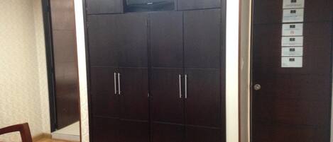 Een kamer met een grote kast, een klein tafeltje en een stoel.