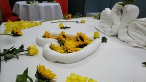 Una mesa adornada con flores amarillas y cisnes blancos.