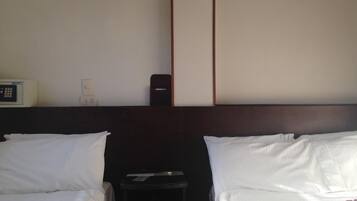 A hotel room with two beds, a bedside table, a small cabinet, and a wall-mounted telephone.