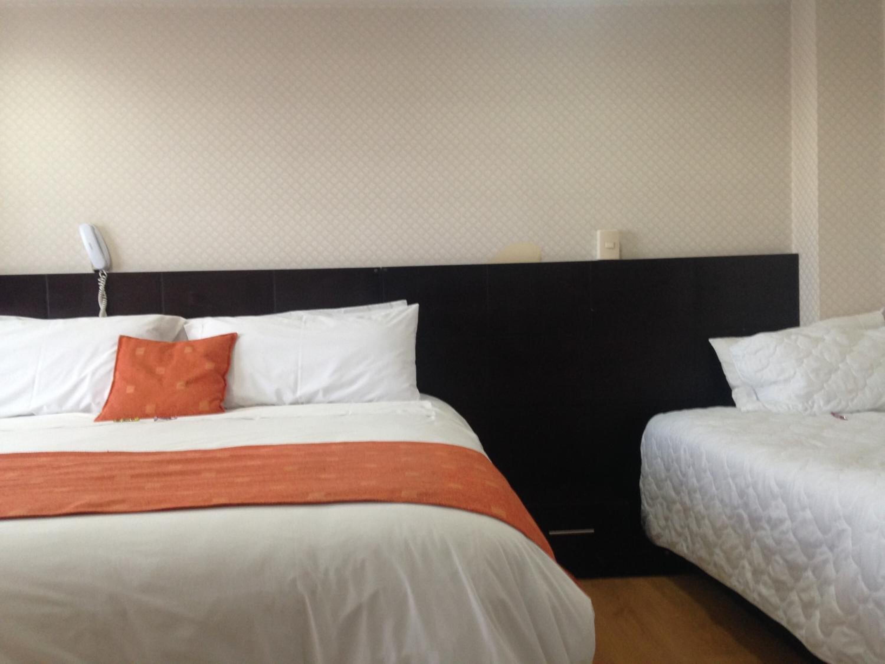 A hotel room with two beds, a black headboard, and a white wall.