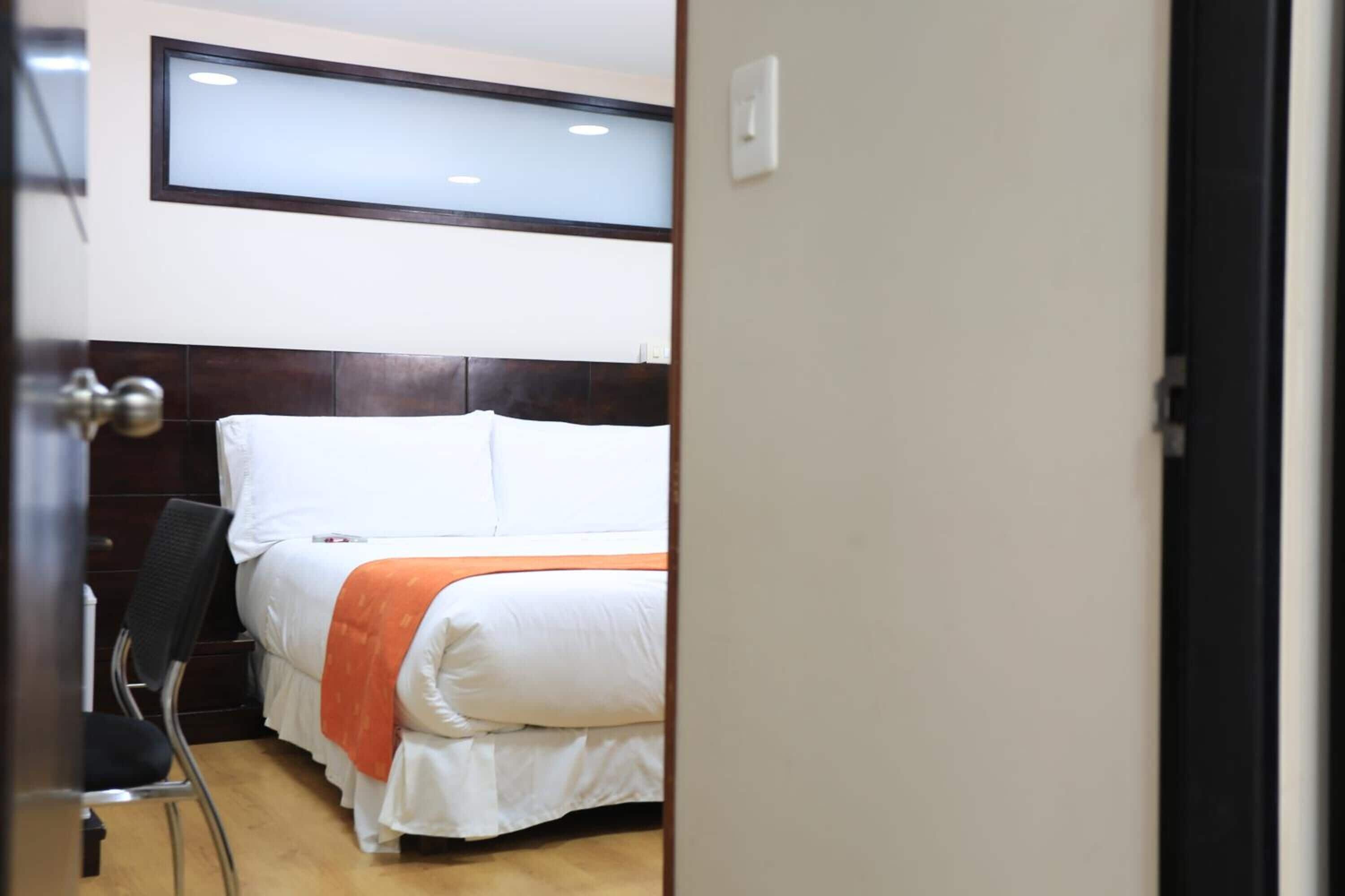 Una habitación de hotel con una cama, una silla y una ventana.