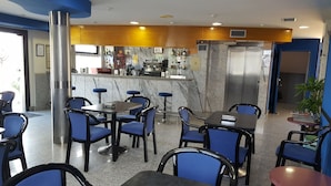 A restaurant with marble walls, blue chairs, and a bar area with various bottles.