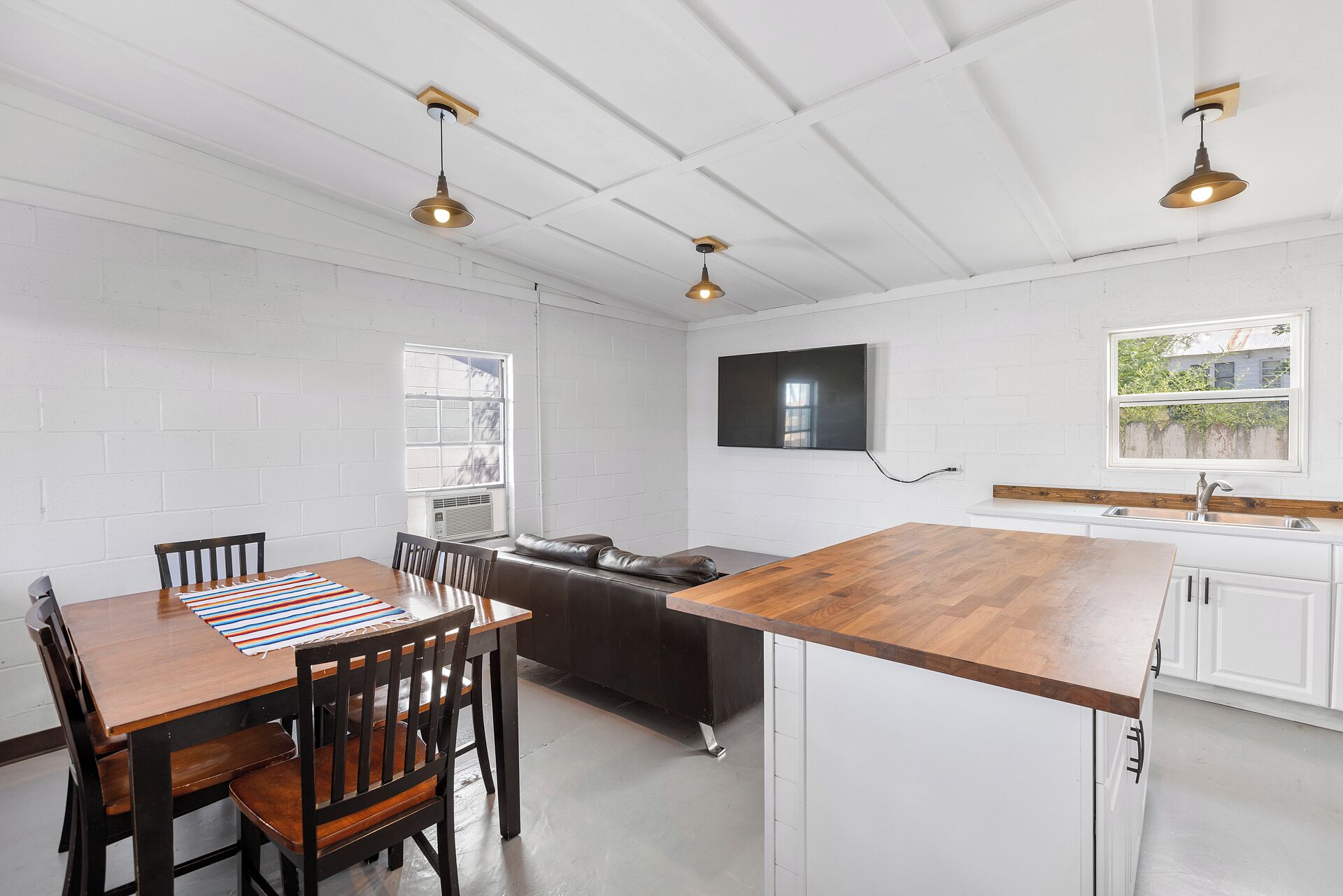 Una cocina moderna con armarios blancos, encimera de madera e iluminación colgante.