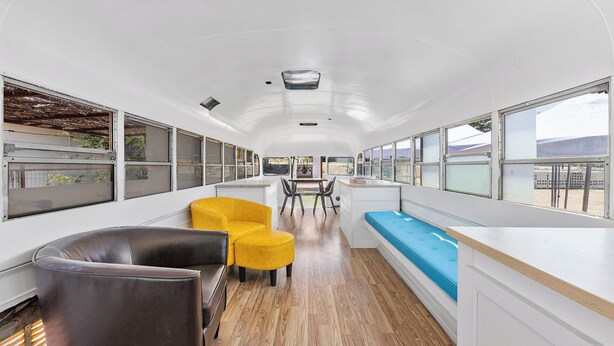 A modern interior with a central dining area, yellow and black seating, and large windows offering views. - Desert Air Motel (Sanderson)
