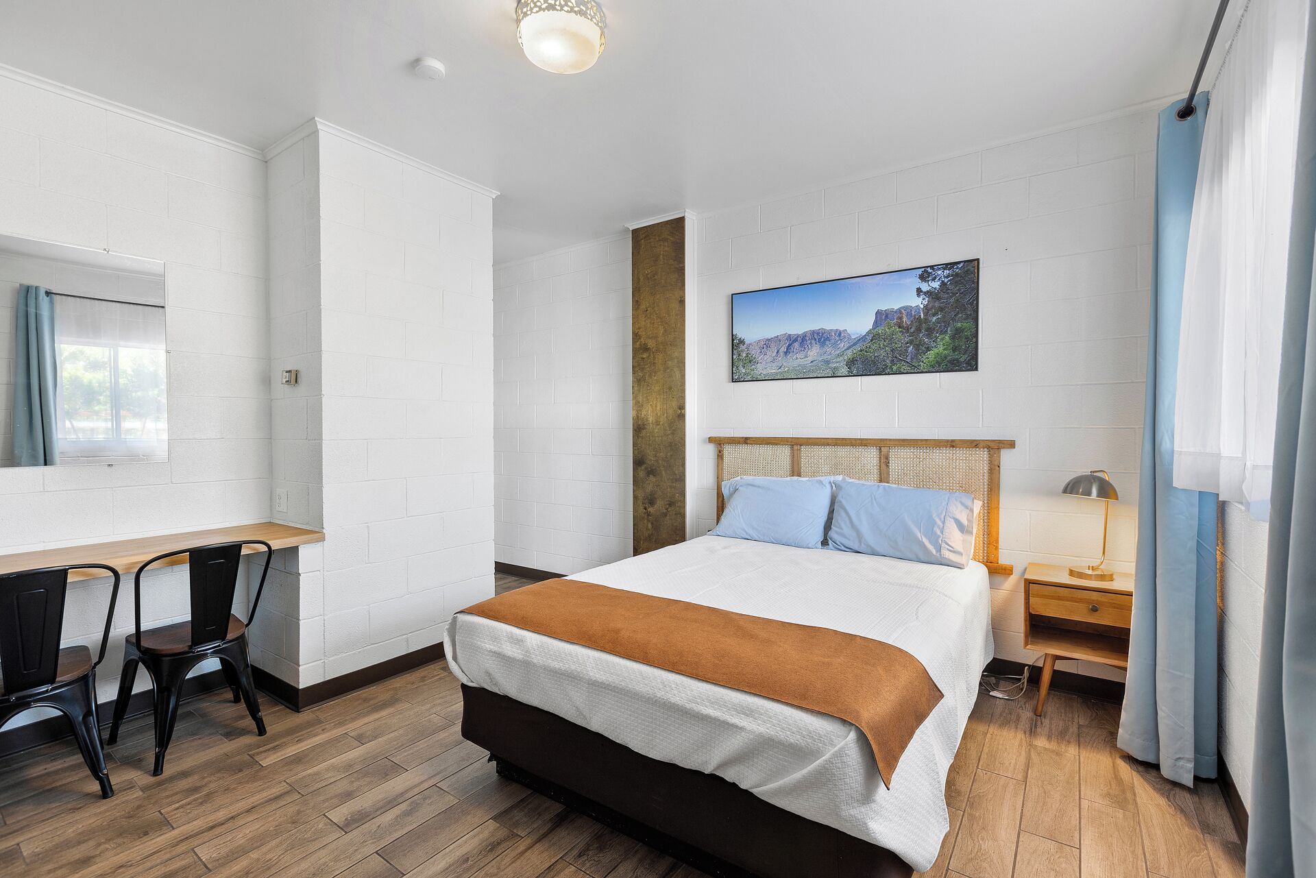 Une chambre d’hôtel équipée d’un lit, d’un bureau, de chaises et d’une table de chevet.