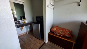 A compact kitchen with a refrigerator, microwave, and a sink. There is a small wooden shelf with a cushion. - Starway Inn (Lansing)