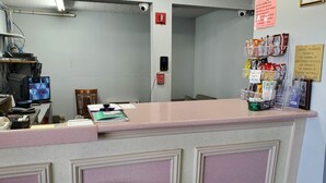 A reception desk with a computer monitor, a chair, and various items on the counter. - Starway Inn (Lansing)