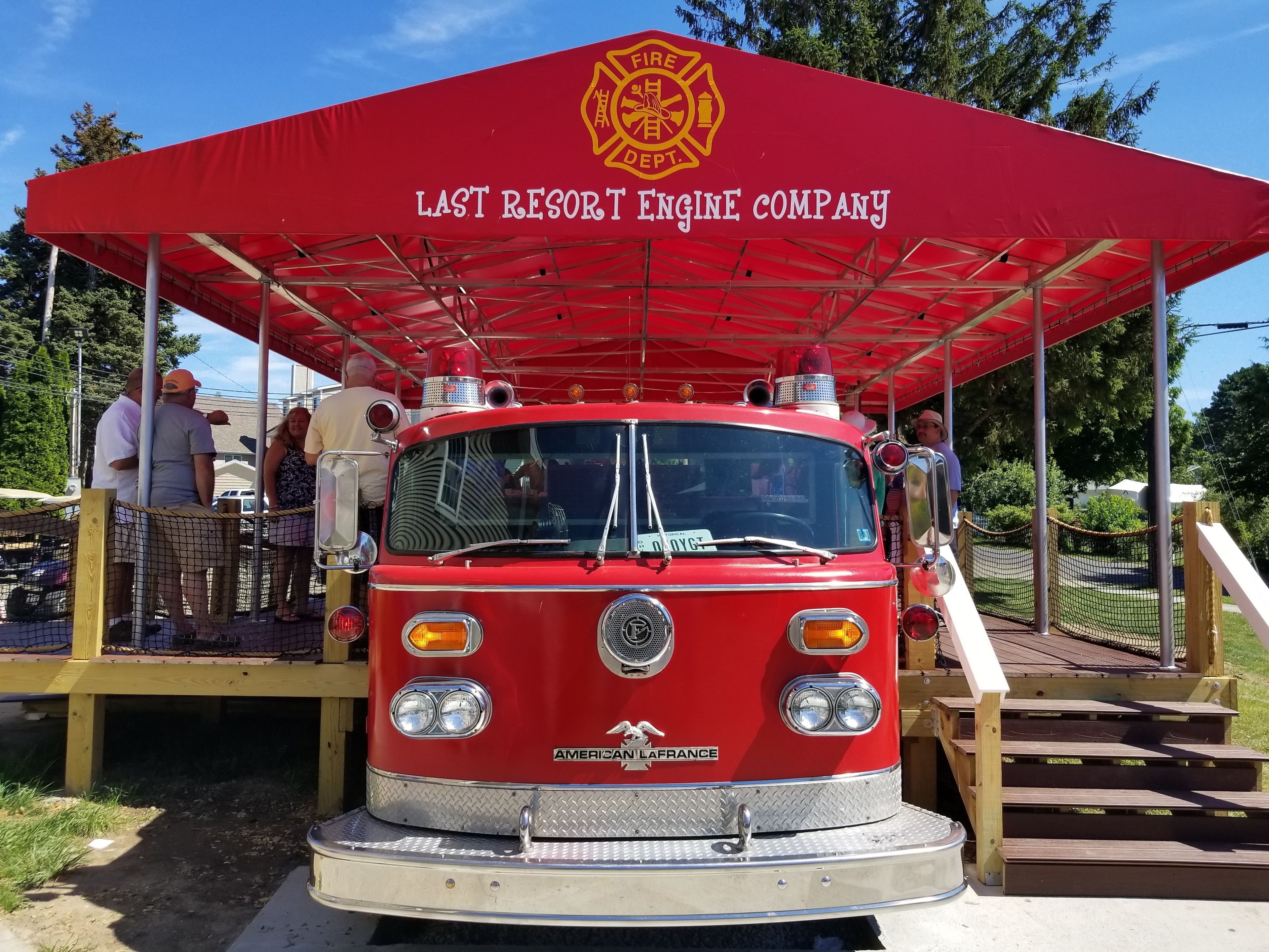 A vintage fire truck with a red canopy labeled "LAST RESORT ENGINE COMPANY" parked outdoors.
