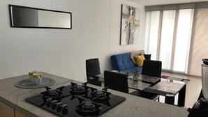 Une cuisine moderne avec une cuisinière à gaz, une table à manger, des chaises et un canapé bleu en arrière-plan.