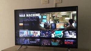 Un téléviseur affichant plusieurs services de diffusion en continu, notamment Netflix, posé sur un meuble en bois.