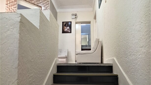 A staircase with a carpeted landing and a wall-mounted clock.