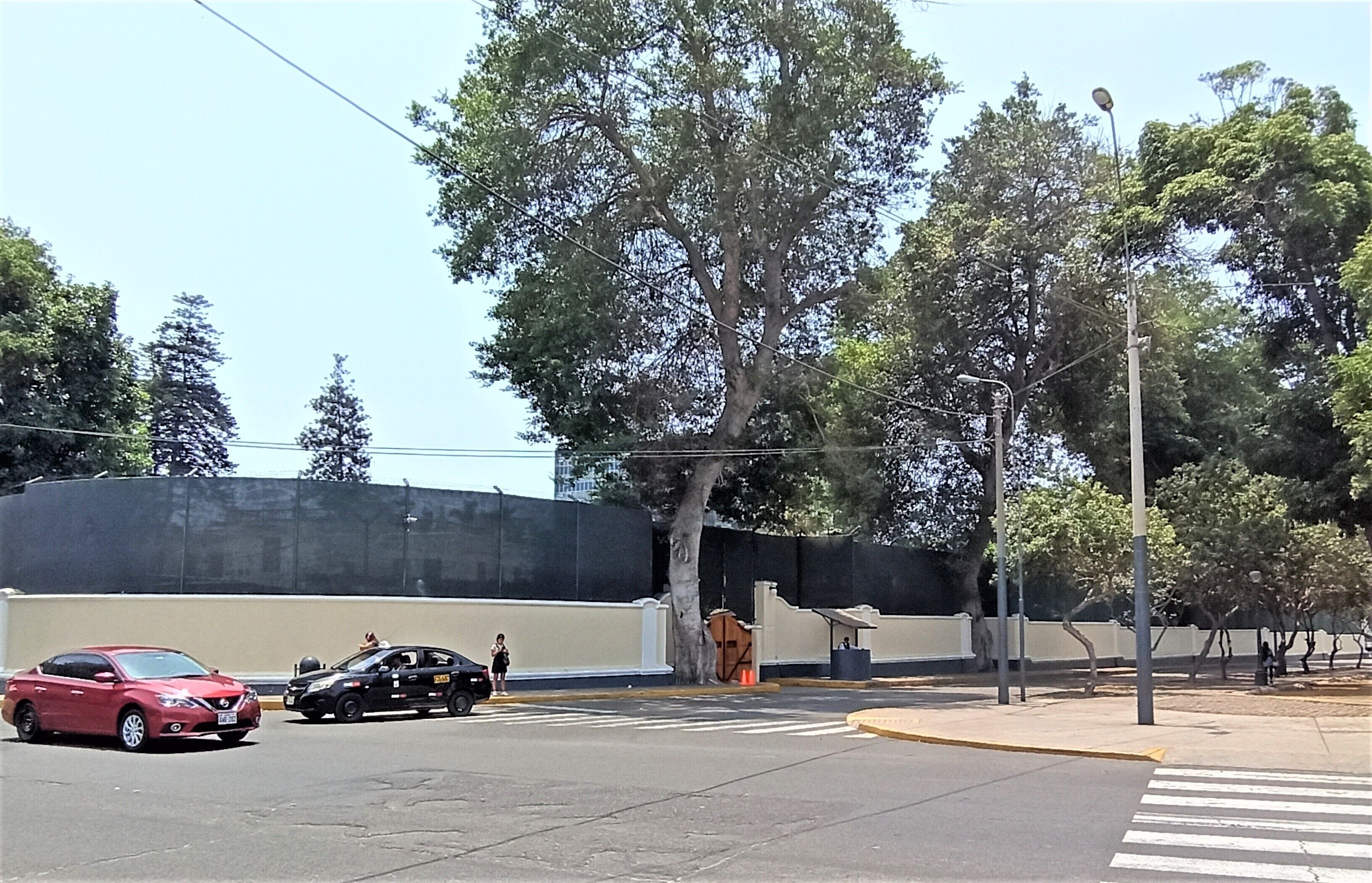 Un estacionamiento con autos, un paso de peatones y árboles.