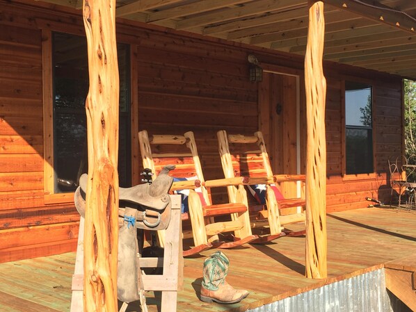 A wooden cabin with a porch, a rocking chair, and a pair of boots.