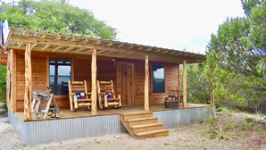 Una cabaña de madera con un porche, una puerta y una ventana.