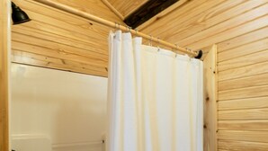 Une salle de bain rustique, avec des murs en bois, comprenant une douche et une serviette accrochée au mur.