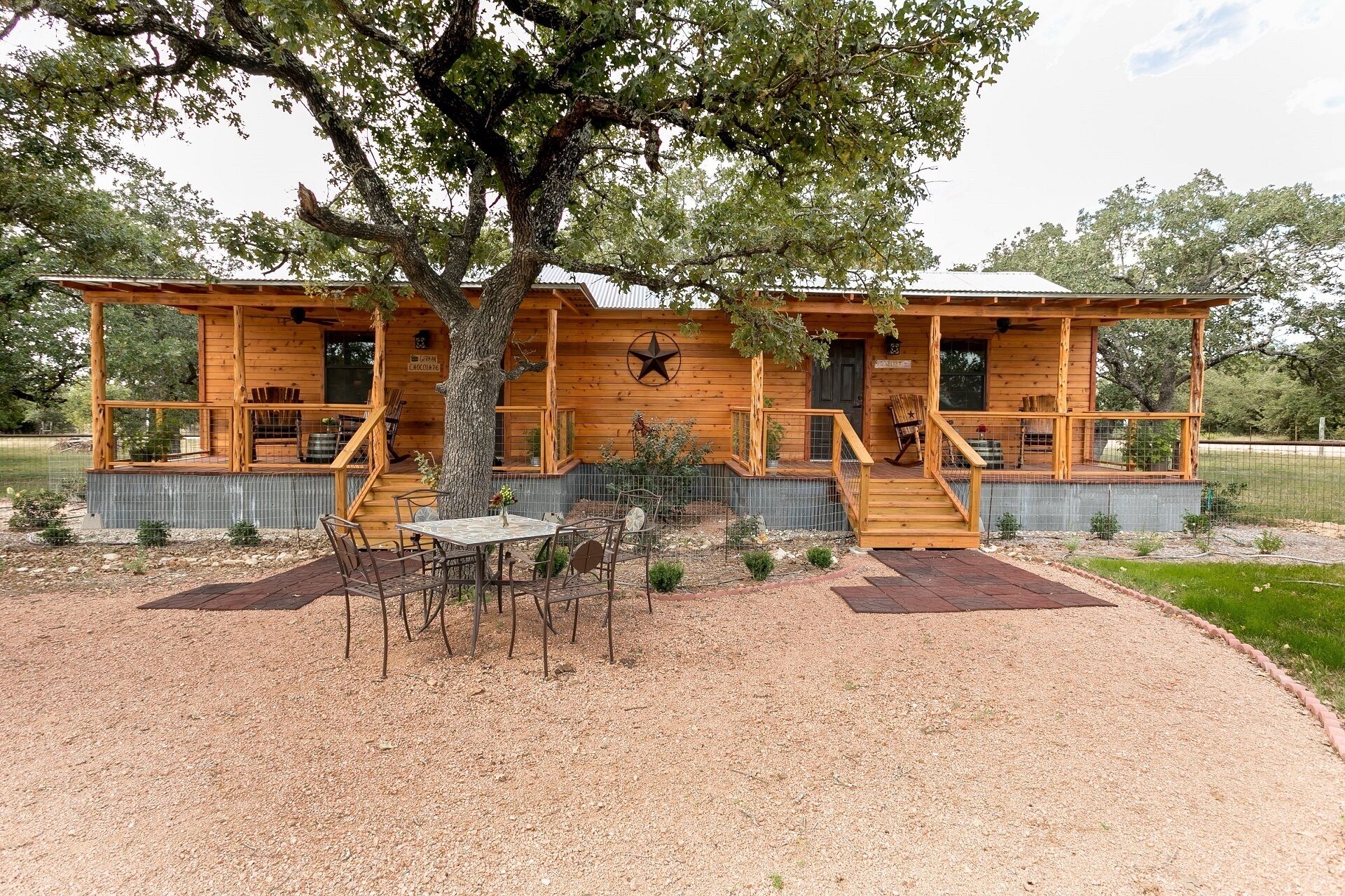 A wooden cabin with a porch, a dining table, and chairs.