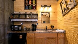 Une cuisine de taille réduite, dotée de meubles en bois, d’un four à micro-ondes, d’une machine à café et d’un évier.