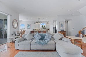 A spacious living room with a large grey sectional sofa, a dining area with wooden chairs, and a kitchen with white cabinets. - Bay Front with Private Pool - North Island - 3BR Dock Holiday (Fort Myers Beach)