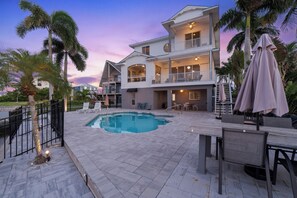 A two-story house with a swimming pool, outdoor furniture, and a view of the sunset. - Bay Front with Private Pool - North Island - 3BR Dock Holiday (Fort Myers Beach)