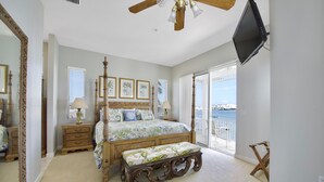 A bedroom with a four-poster bed, a large mirror, a ceiling fan, and a balcony with a view of the water. - Bay Front with Private Pool - North Island - 3BR Dock Holiday (Fort Myers Beach)