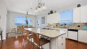 A spacious kitchen with a large island, white cabinetry, and a view of the ocean. - Bay Front with Private Pool - North Island - 3BR Dock Holiday (Fort Myers Beach)