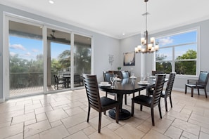 A spacious dining area with a large table, chairs, and a chandelier. - Grande Palermo – Come stay and experience coastal living at its best! (Fort Myers Beach)