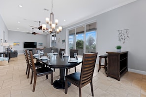 A dining area with a round table, chairs, and a chandelier. - Grande Palermo – Come stay and experience coastal living at its best! (Fort Myers Beach)