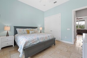A bedroom with a bed, nightstands, a door, and a view of a living area. - Grande Palermo – Come stay and experience coastal living at its best! (Fort Myers Beach)