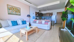 Una sala de estar moderna con un sofá, una mesa de centro y una cocina al fondo.
