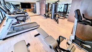 Un gimnasio moderno con cintas de correr, máquinas de pesas y un espejo grande.
