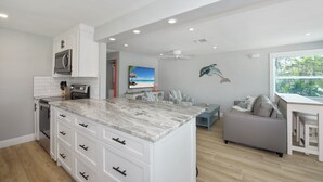 A modern kitchen with white cabinetry, a marble countertop, and built-in appliances.