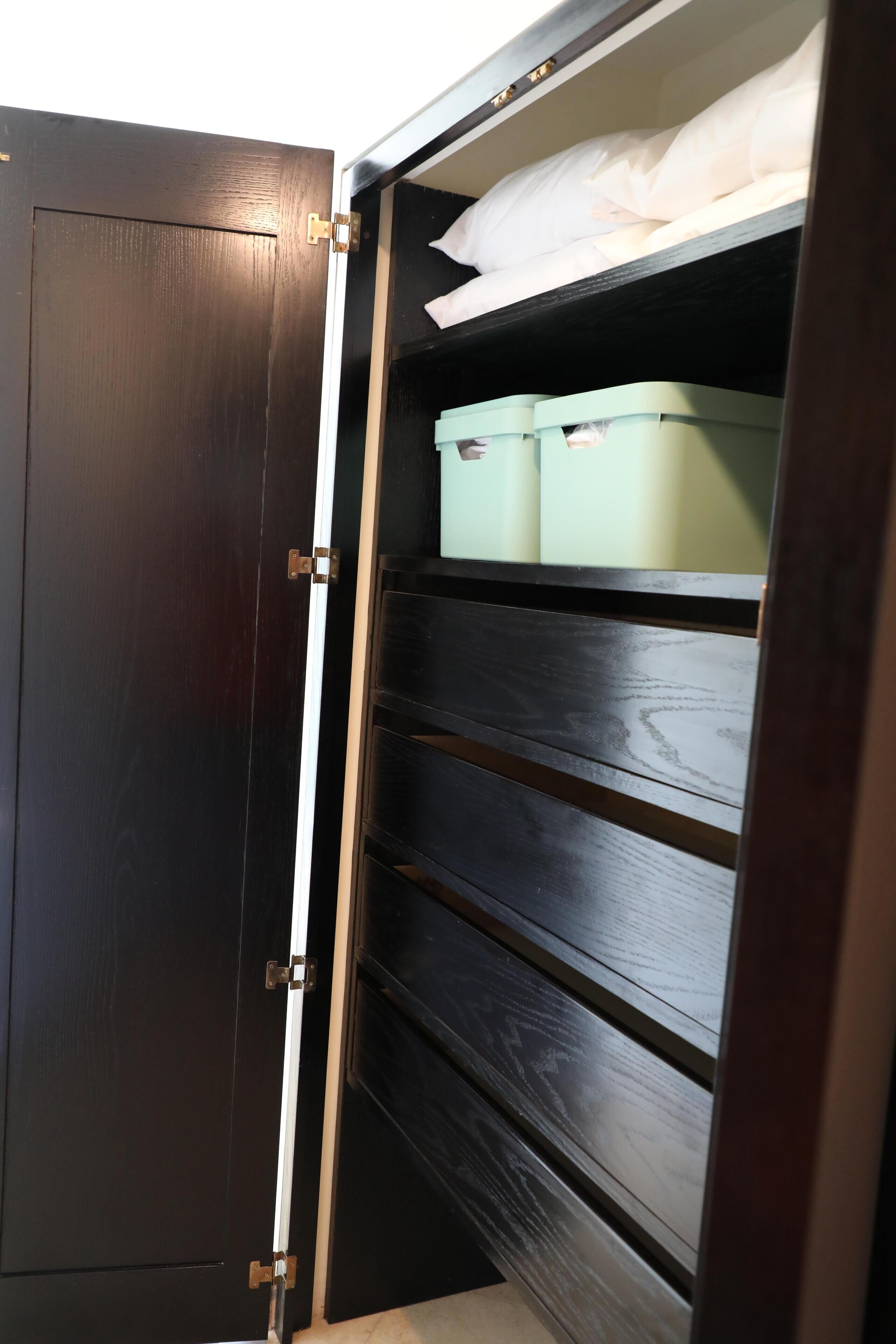 A dark wooden wardrobe with multiple shelves and a hanging rod.