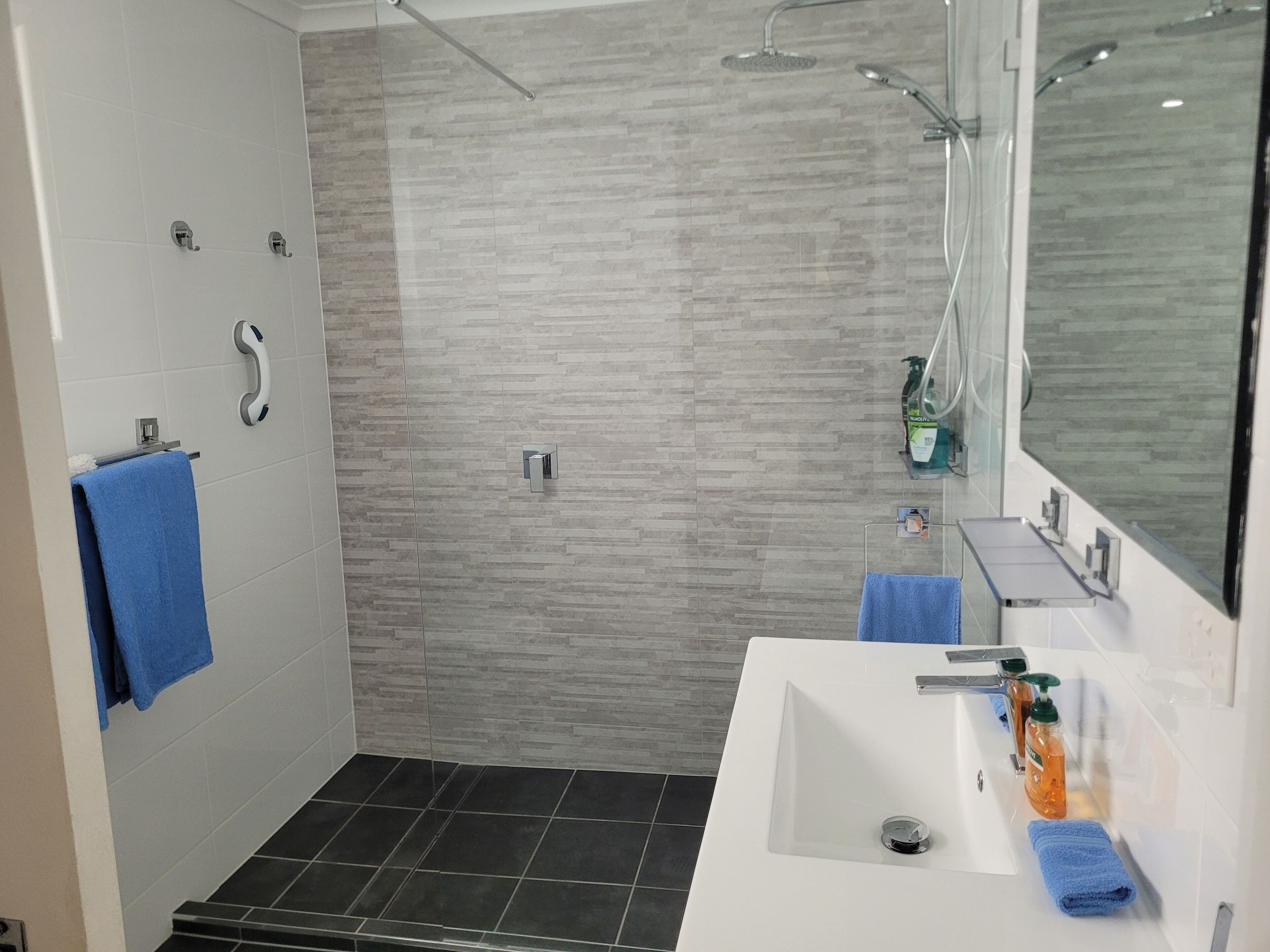Een moderne badkamer met een douche, wastafel en spiegel.