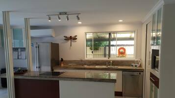 A modern kitchen with a central island, stainless steel appliances, and a window with a view of greenery.