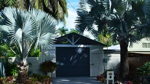 Eine Garage mit Metalldach, umgeben von Pflanzen und einem Weg.