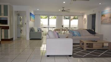 A spacious living area with a white sofa, a coffee table, and a ceiling fan.