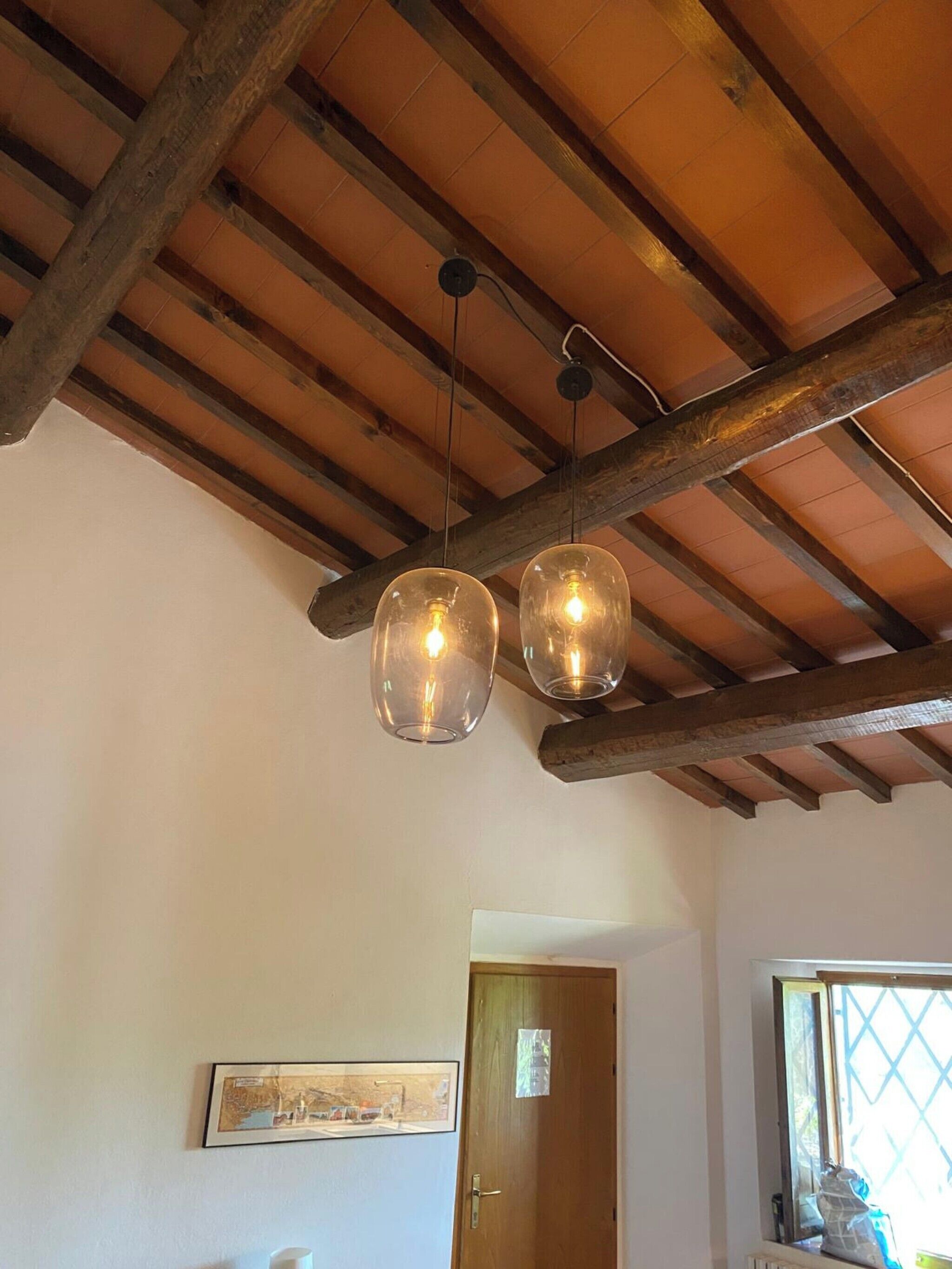 A room with exposed wooden beams, a wooden door, and a framed picture on the wall.