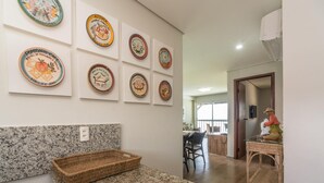 Une cuisine dotée de plans de travail en granit, d’un panier en osier et d’un mur orné de diverses assiettes décoratives.