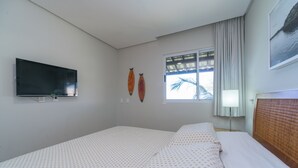 Une chambre d’hôtel équipée d’un lit, d’un téléviseur à écran plat, d’une fenêtre avec des rideaux et de décorations murales.