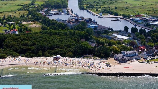 Vista aérea de un pueblo costero con playa, río y edificios industriales.
