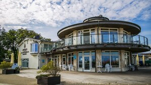 Un edificio frente al agua con un balcón circular, asientos al aire libre y un letrero que dice "Apollo".
