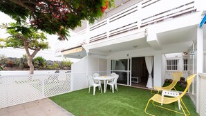 Un balcon avec une balustrade blanche, une table avec des chaises et une chaise jaune.