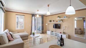 A modern living room with a sofa, dining table, TV, and decorative items.