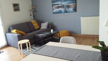 A modern living room with a sofa, coffee table, and a dining table.