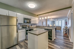 A modern kitchen with stainless steel appliances, a central island, and pendant lighting.