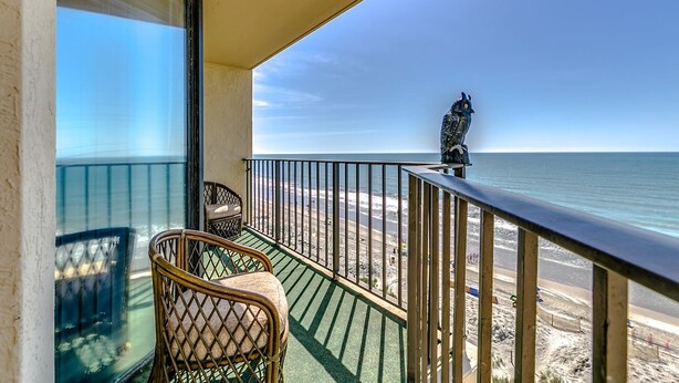 Ein Balkon mit Blick auf Strand und Meer.