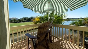 Una terraza de madera con vista a un lago, una silla y un paraguas a rayas.